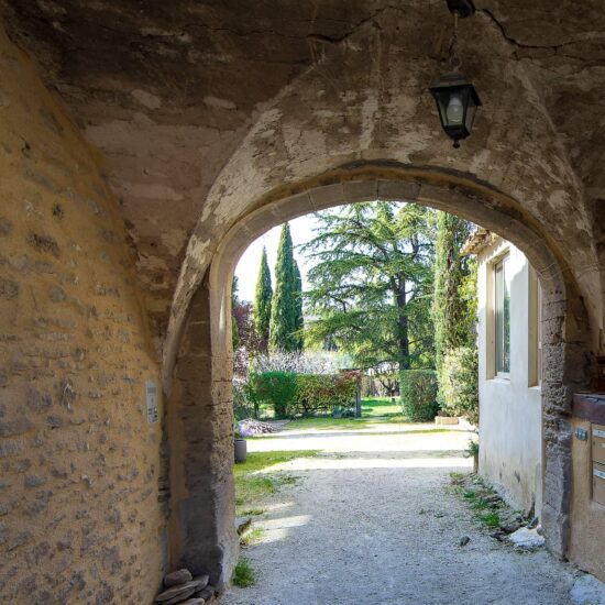 Après le porche d'entrée vouté en pierre de la bâtisse de locations saisonnières, la cour et un jardin luxuriant se dévoilent.